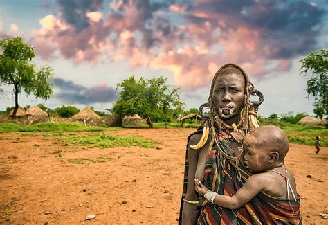 African Mother From The Mursi Tribe Carrying Her Infant In Ethiopia