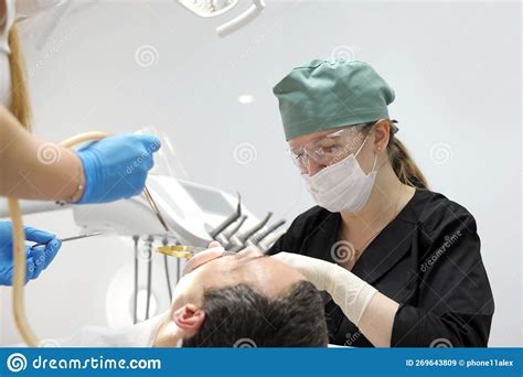 Cheerful Female Dentist Holding Drill And Smiling Near Patient Stock