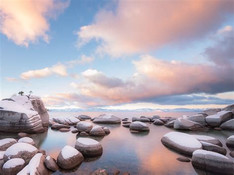 Snow Covered Rocks On Body Of Water Under Blue And White Cloudy Sky
