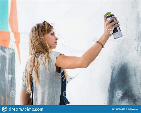 Beautiful Young Blonde Girl Making Graffiti Of Big Eye With Aerosol