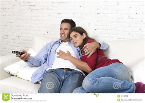 Couple In Love Cuddling On Home Couch Relaxing Watching Movie On