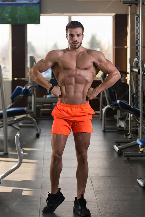 Hombre Musculoso Flexionando Los Músculos En El Gimnasio Foto Premium