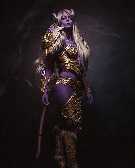 A Woman Dressed In Purple And Gold Is Posing For The Camera With Her