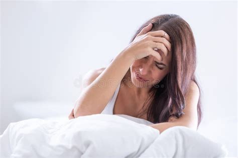 Woman Wakes Up In Bed With Severe Migrene Holding Her Head Stock Image