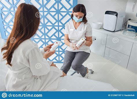 Doctor Cosmetologist Discussing Skincare Products With Patient Stock