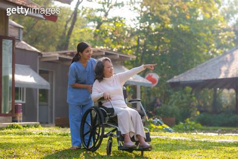 Asian Nurse Takes A Patient In A Wheelchair To Make Her Feel Refreshed And Relaxed At The Park