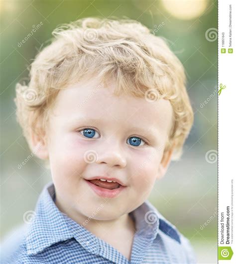 Close Up Portrait Of Cute Happy Smiling Baby Boy In Blue Shirt On Green