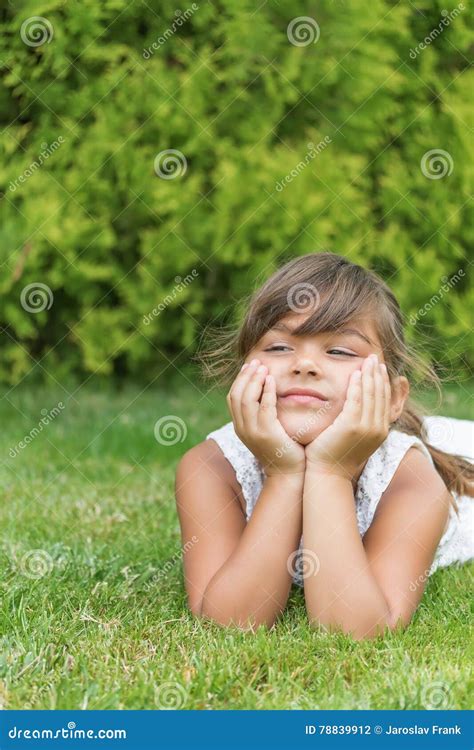 Attractive Little Girl Lying On A Lawn Vertically Stock Photo Image