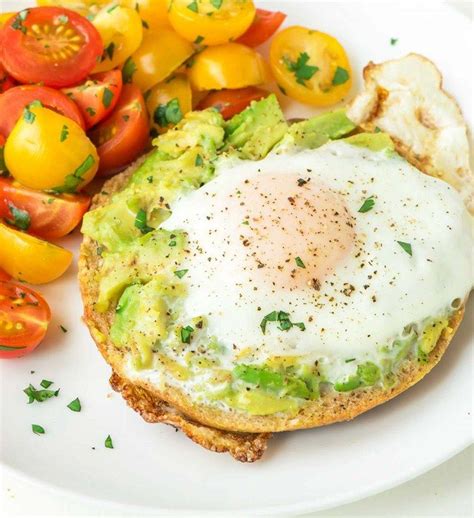 An Egg And Avocado Toast With Tomatoes On The Side