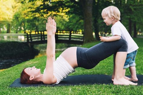 premium photo beautiful pregnant woman doing yoga with little son on nature outdoors