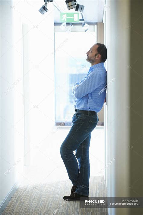 Mature Man Leaning Against Wall In Corridor Male Time Stock Photo