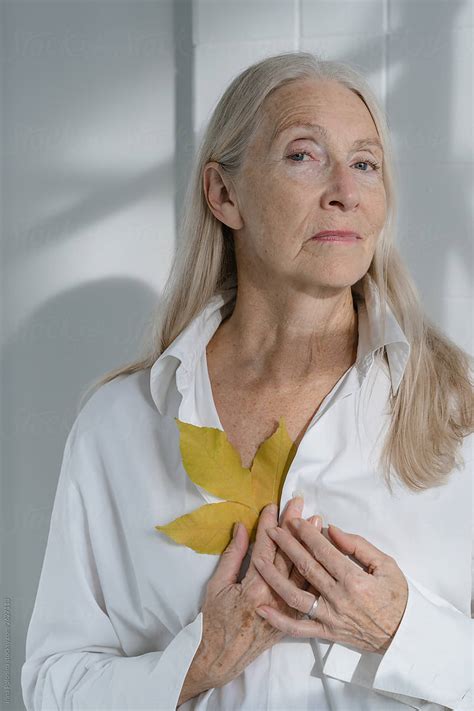 Portrait Of A Senior Woman With Grey Long Hairs With Yellow Leaf By Stocksy Contributor Irina