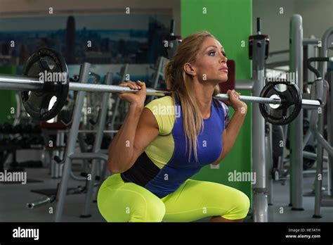 Mature Woman Working Out Legs With Barbell In A Gym Squat Exercise