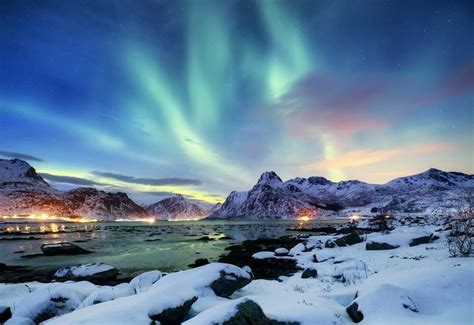 An Aurora Bore Over The Mountains At Night With Snow On Rocks And
