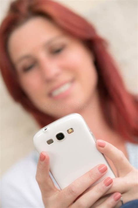 Pretty Smiling Redhead Woman Sending Messages Or Make A Selfie On Her Cell Phone Stock Image
