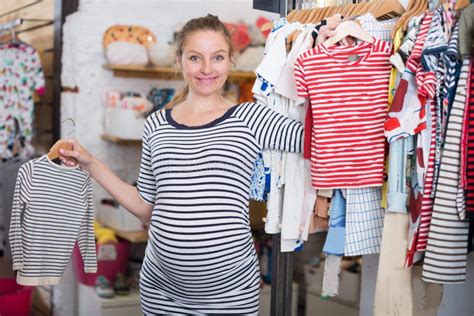 Pregnant Woman In Striped Tunic Chooses Shirt In Clothing Shop Stock Image Image Of Happy