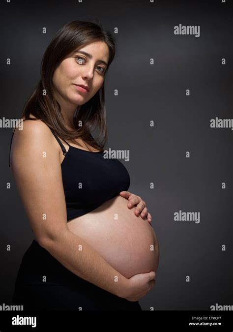 A Pregnant Woman Holds Her Big Belly Over A Gray Background Stock Photo