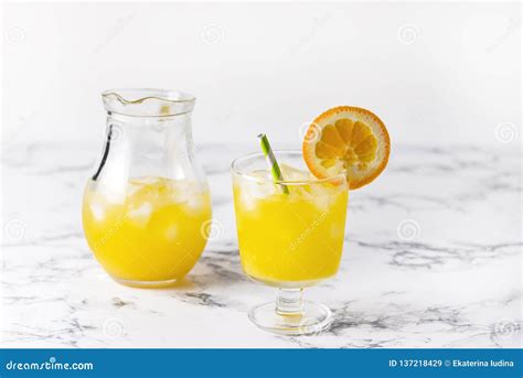 Tasty Orange Juice In Glass With Ice Cube Blue And White Background