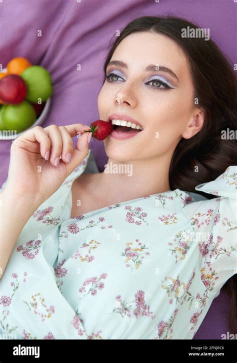 Pretty Smiling Girl Eats Strawberry Close Up Portrait Of The Beautiful Young Woman In Dress