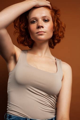Young Pretty Redhead Girl Posing Cheerful On Warm Brown Background