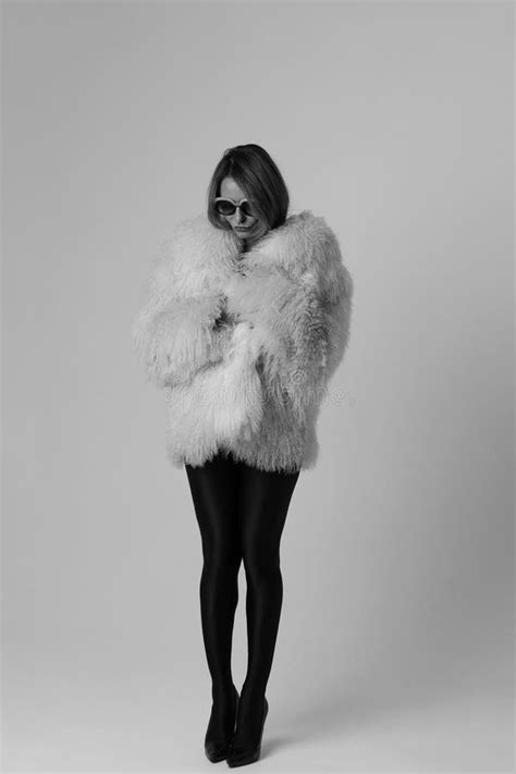 Portrait Of Young Woman Wearing White Fur Coat Posing Indoor Black And