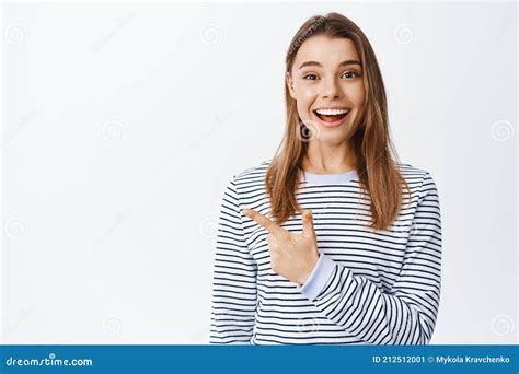 Portrait Of Excited Girl With Hopeful Face And Happy Smile Pointing Finger Left At Logo Banner