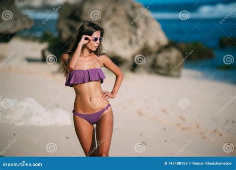 Slender Tanned Girl In Swimsuit Posing On Beach With Sand And Large