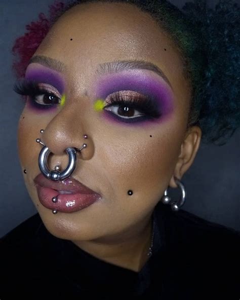 A Woman With Purple And Yellow Makeup Has A Nose Ring On Her Nose While