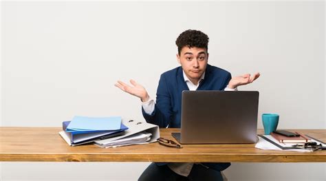 Premium Photo Business Man In A Office Having Doubts While Raising Hands
