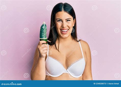 Beautiful Brunette Woman Holding Condom On Cucumber For Sex Education