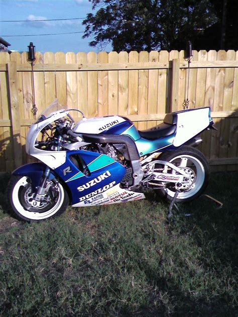 A Blue And White Motorcycle Parked Next To A Wooden Fence