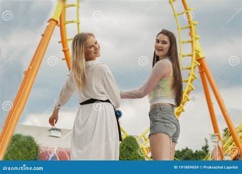 Two Caucasian Teenage Girls Enjoy At Theme Park A Roller Coaster On