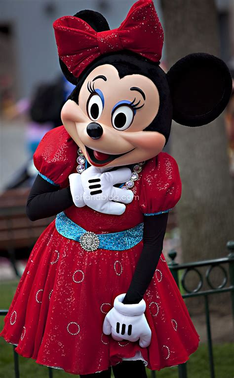 a woman in a minnie mouse costume poses for a photo at the disneyland world park