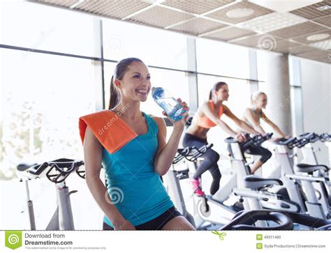 Group Of Women Riding On Exercise Bike In Gym Stock Photo