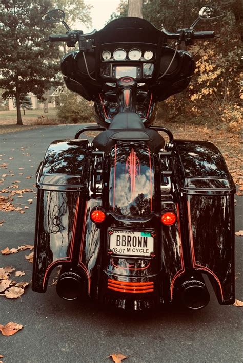 The Back End Of A Motorcycle Parked In Front Of Some Leaves On The