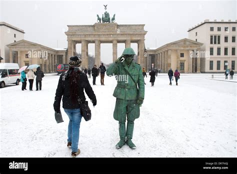 A Street Artist Depicting A Gdr Soldier Stands Infront Of Brandenburg