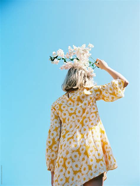 Blonde Girl With Yellow Floral Dress Against Blue Sky With Flowers On