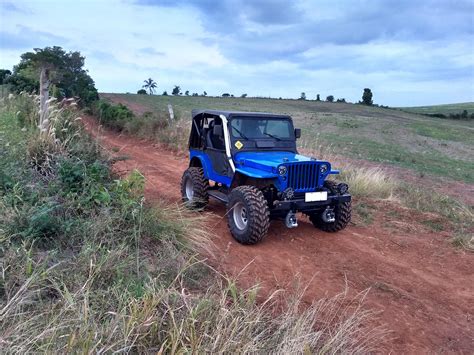 A Blue Jeep Driving Down A Dirt Road