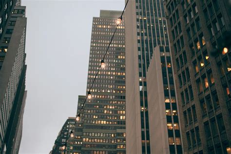 Modern Skyscraper Facades Near Shiny Garland In Evening · Free Stock Photo