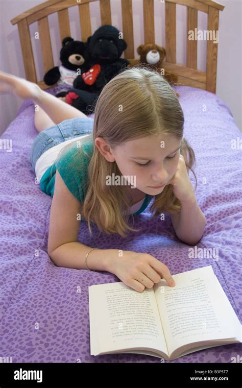 Young Girl Lying On Bed Sur Son Ventre La Lecture Dun Livre Photo