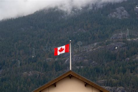 A Picture Of Canada Flag Waving Against The Mountain Stock Photo