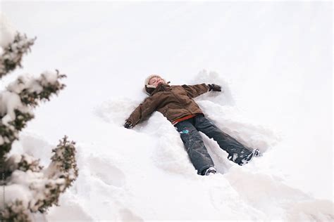 Young Boy Making A Snow Angel By Stocksy Contributor Lea Csontos
