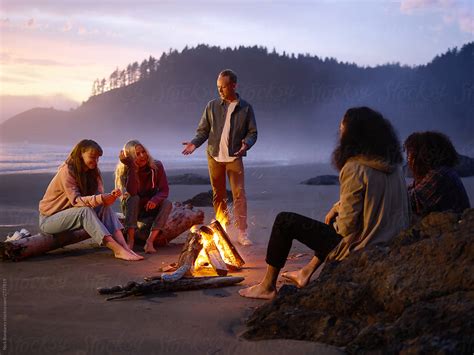 Friends Relaxing Around Bonfire On Beach By Nick Bondarev