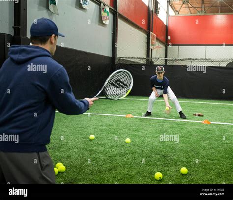 Baseball Coach Doing Fielding Drills At An Indoor Training Facility In