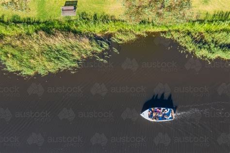 Image Of Aerial View Of A Small Boat Cruising Along A City River