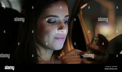 Passenger Girl In The Back Seat Of A Car Typing On Her Cellphone At