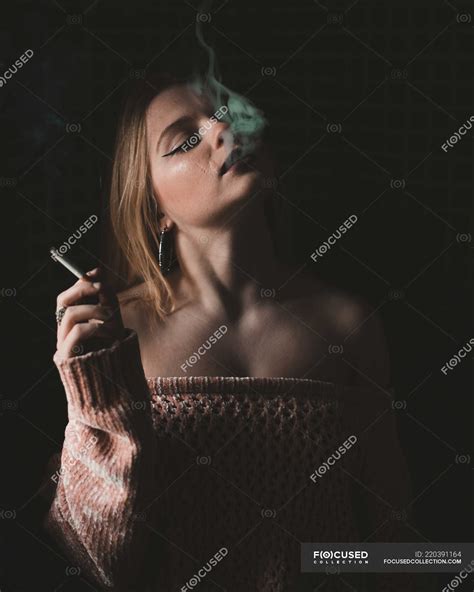 Atraente jovem sensual mulher fumar cigarro no fundo escuro inchaço Lindo Stock Photo