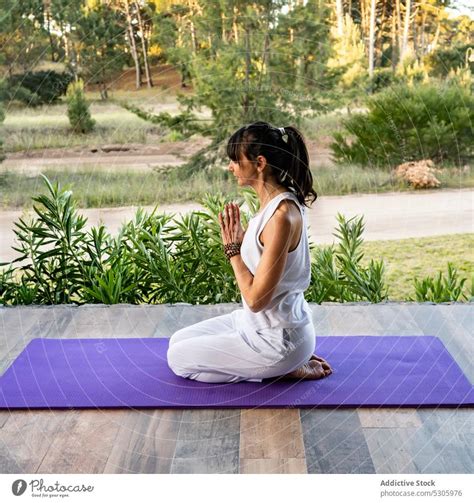 Calm Woman Meditating In Yoga Pose Against Plants A Royalty Free