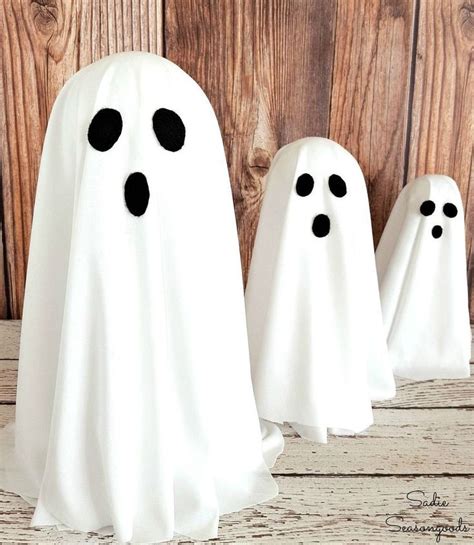 Three White Ghost Statues Sitting Next To Each Other On A Wooden Floor