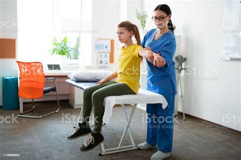 Focused Darkhaired Professional Nurse Stretching Hand Of Her Patient